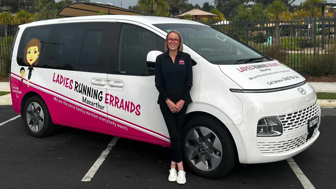Janene standing beside a branded Ladies Running Errands vehicle outdoors.