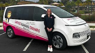 Janene standing beside a branded Ladies Running Errands vehicle outdoors.